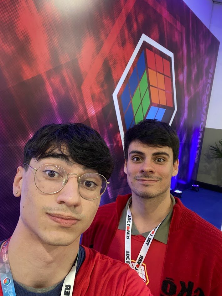 Selfie do Henrique com o Vitor no TDC, em frente ao painel da conferência